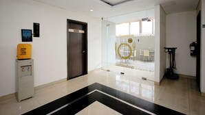 Eine moderne Hotellobby mit Glastrennwand, Wasserspender und Schild für ein Café.