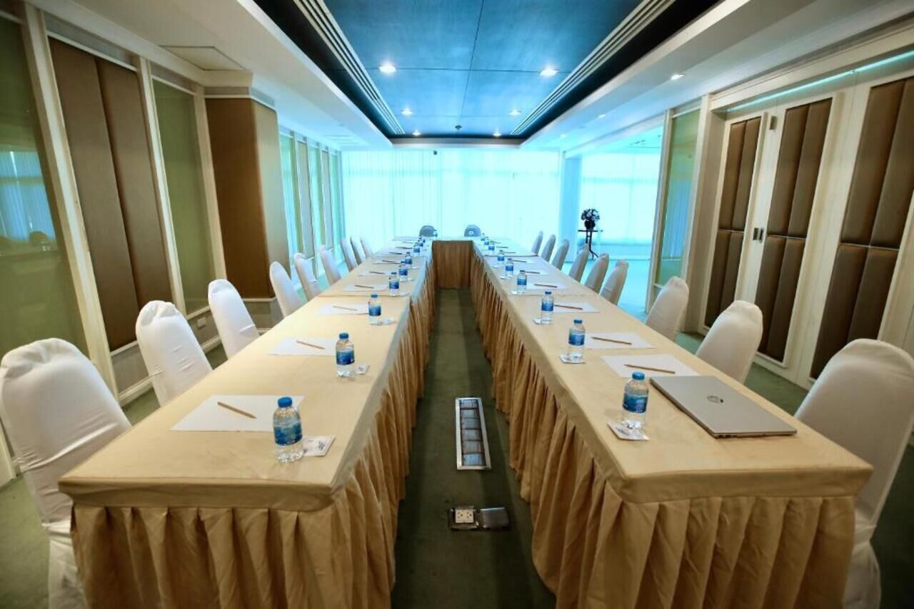A conference room with a long table, chairs, water bottles, and laptops.