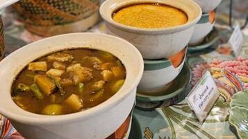 Variedad de platos, incluyendo un tazón de sopa con trozos, un tazón de curry y un tazón de arroz.