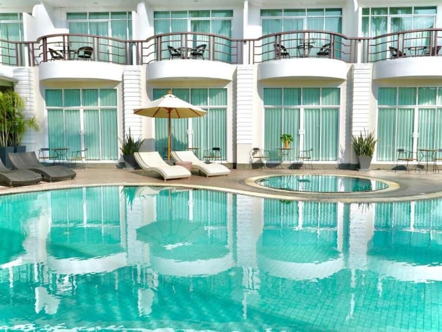 Una piscina al aire libre, sombrillas, sillones reclinables de piscina