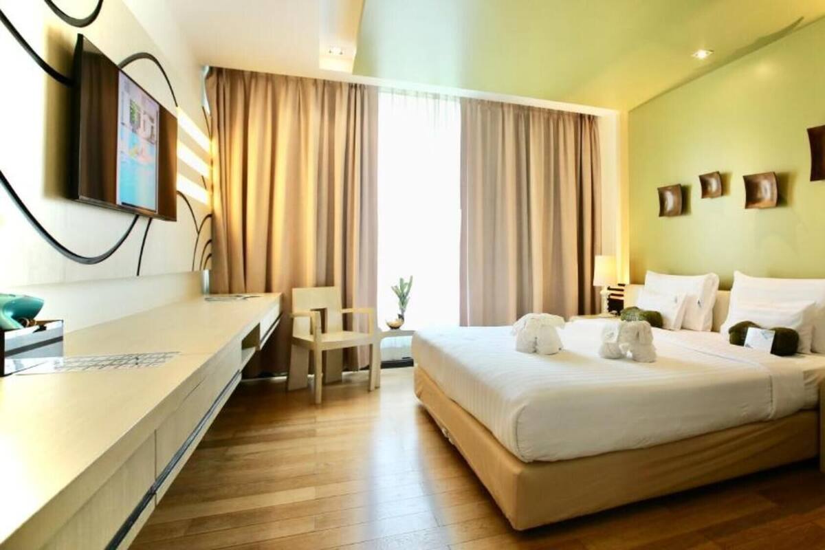 A hotel room with a large bed, a desk, and a chair.