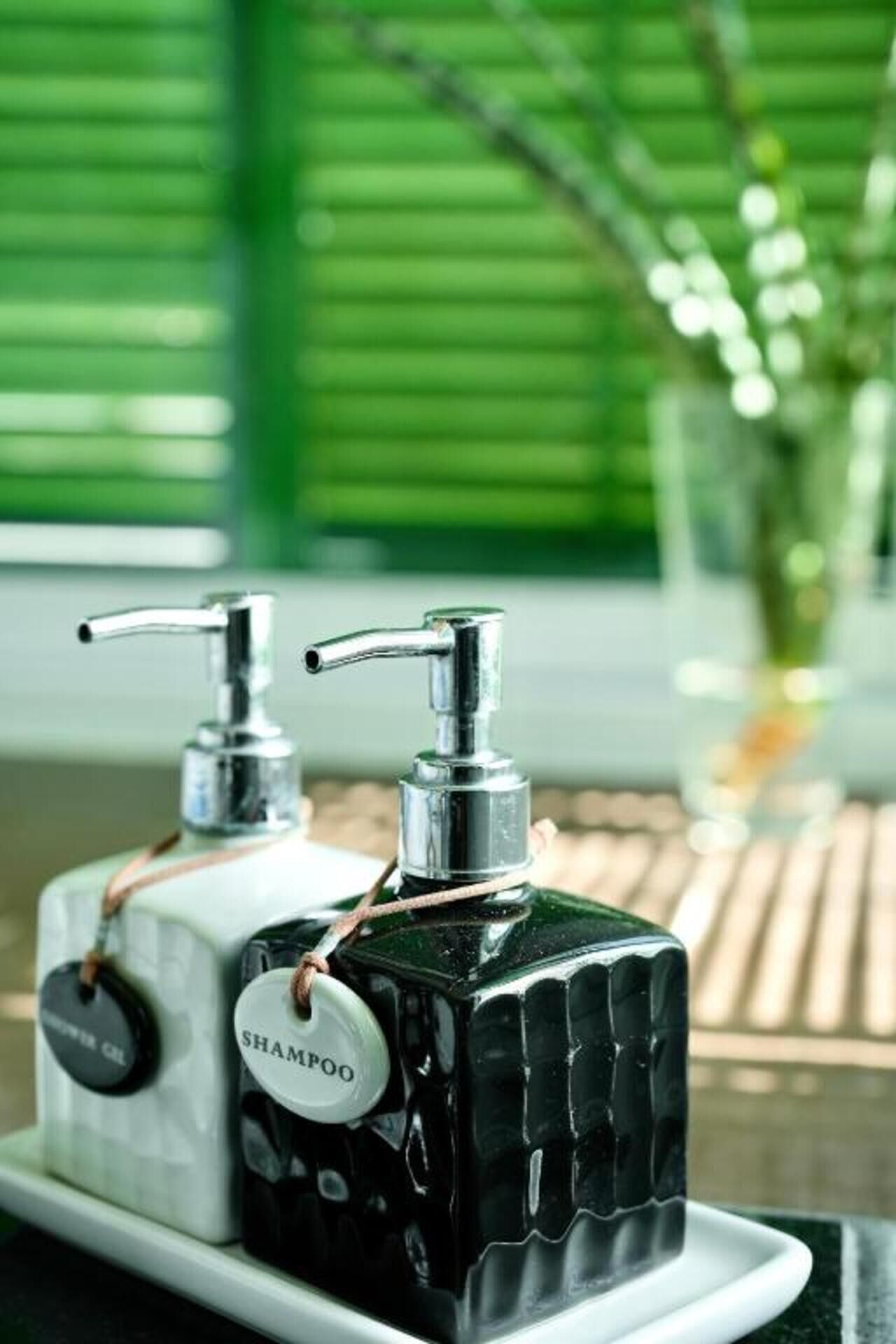 Two shampoo bottles on a tray, one white and one black, with pump dispensers.