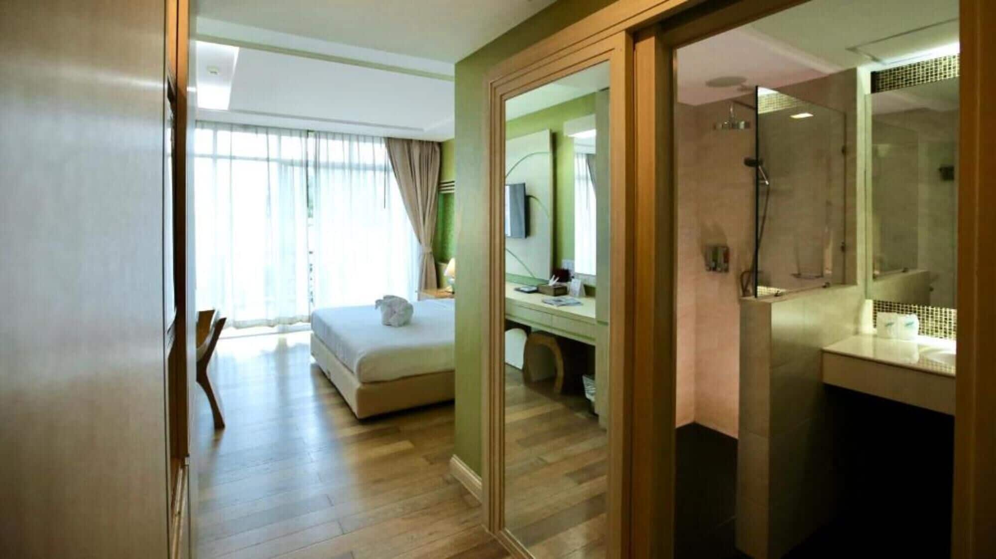 Una habitación de hotel con cama, escritorio, espejo y zona de ducha.