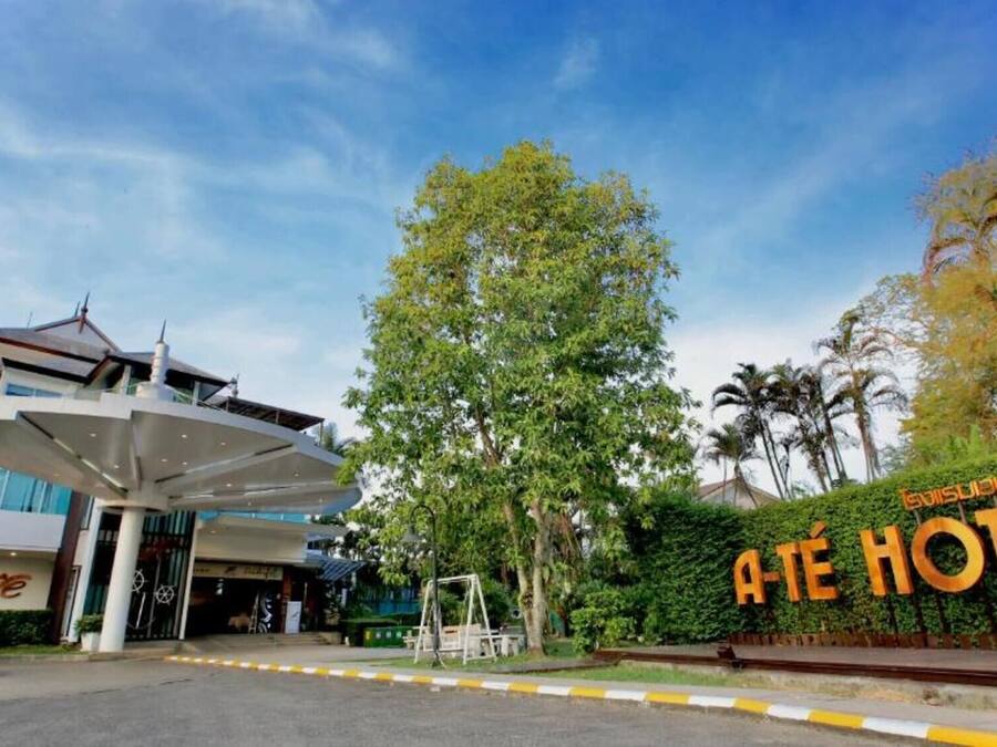A hotel entrance with a modern building, a swing set, and a sign reading "Ate Hotel".