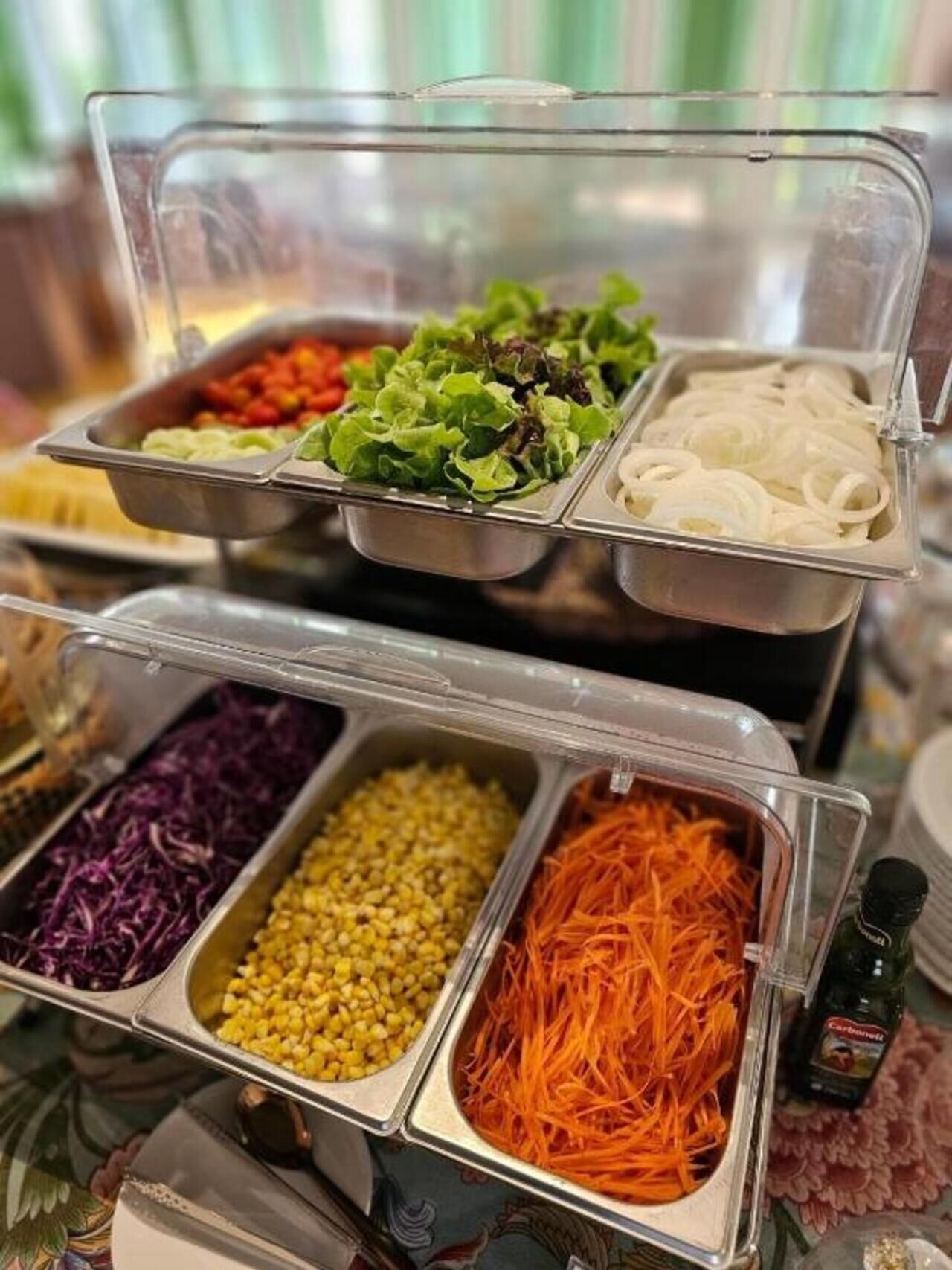 Un bufé con diversas opciones de comida, incluyendo verduras, cereales y zanahorias ralladas.