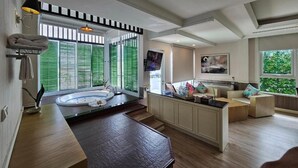 A modern kitchen with a built-in stove, a large window with blinds, and a dining area with a wooden table.