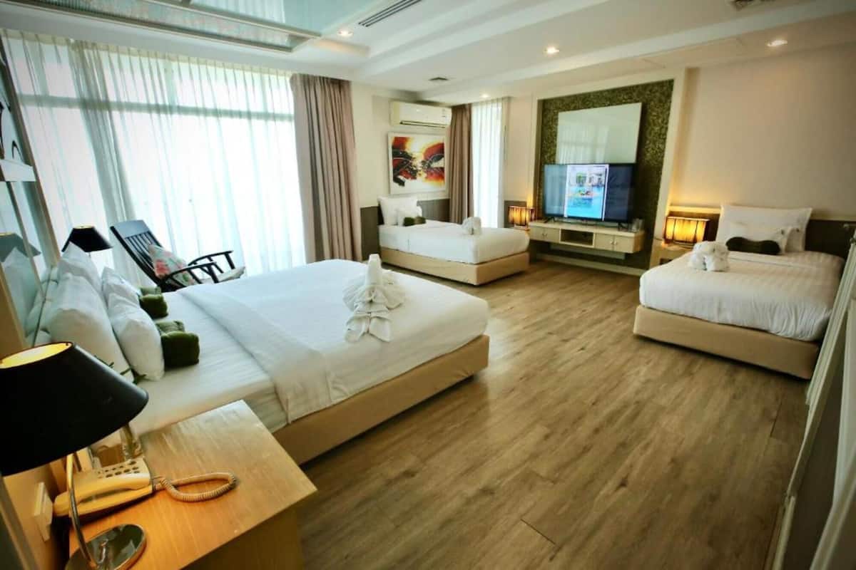 A hotel room with two single beds, a desk with a telephone, a TV, and a large window with curtains.