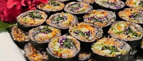 Un plato de sushi con diferentes ingredientes, acompañado de una flor roja.