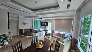 A spacious living area with a dining table, chairs, a sofa, and a TV.