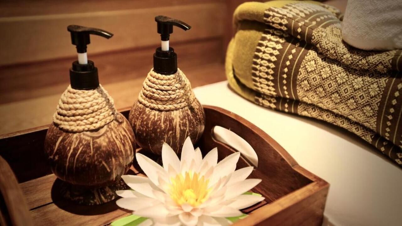 A wooden tray with two soap dispensers and a lotus flower.