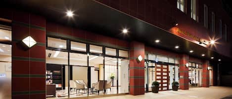 A hotel entrance with a check-in counter, seating area, and a sign indicating the hotel's name.