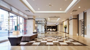 A hotel lobby with a checkered floor, seating area, and a reception desk. - Hotel Hokke Club Kagoshima (Kagoshima)