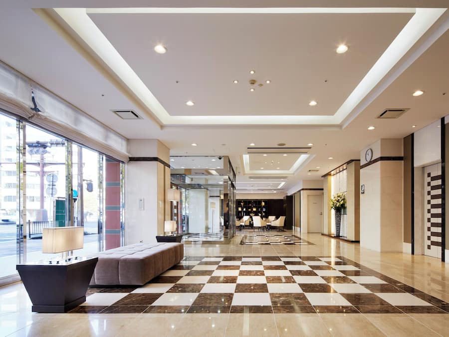 Un hall de hotel con piso a cuadros, área de descanso y mostrador de recepción.