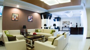 A modern hotel lobby with a high ceiling, a reception desk, and a seating area with sofas and a coffee table. - Bella Hotel Surabaya (Surabaya)