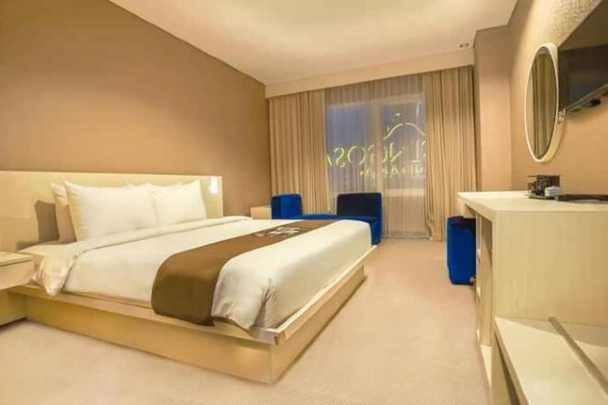 A hotel room with a bed, a desk, a chair, and a large window.