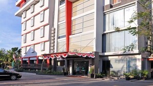 Un hotel de varios pisos con fachada moderna, que destaca por una llamativa combinación de rojo y blanco.
