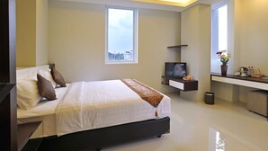Un dormitorio moderno con una cama grande, un televisor, un escritorio pequeño y una ventana.