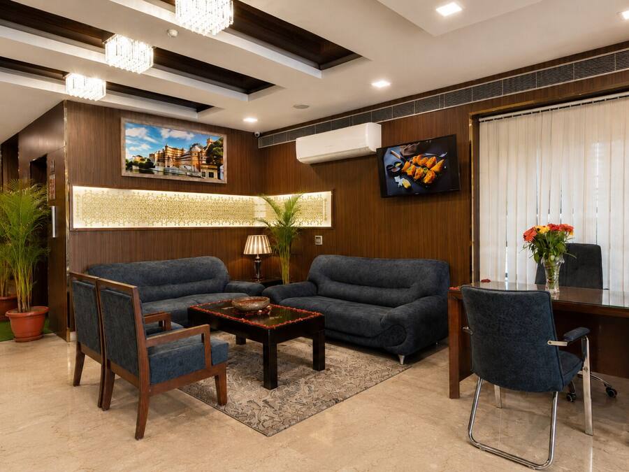 A modern hotel lobby with a sofa set, a coffee table, a desk, and a television.