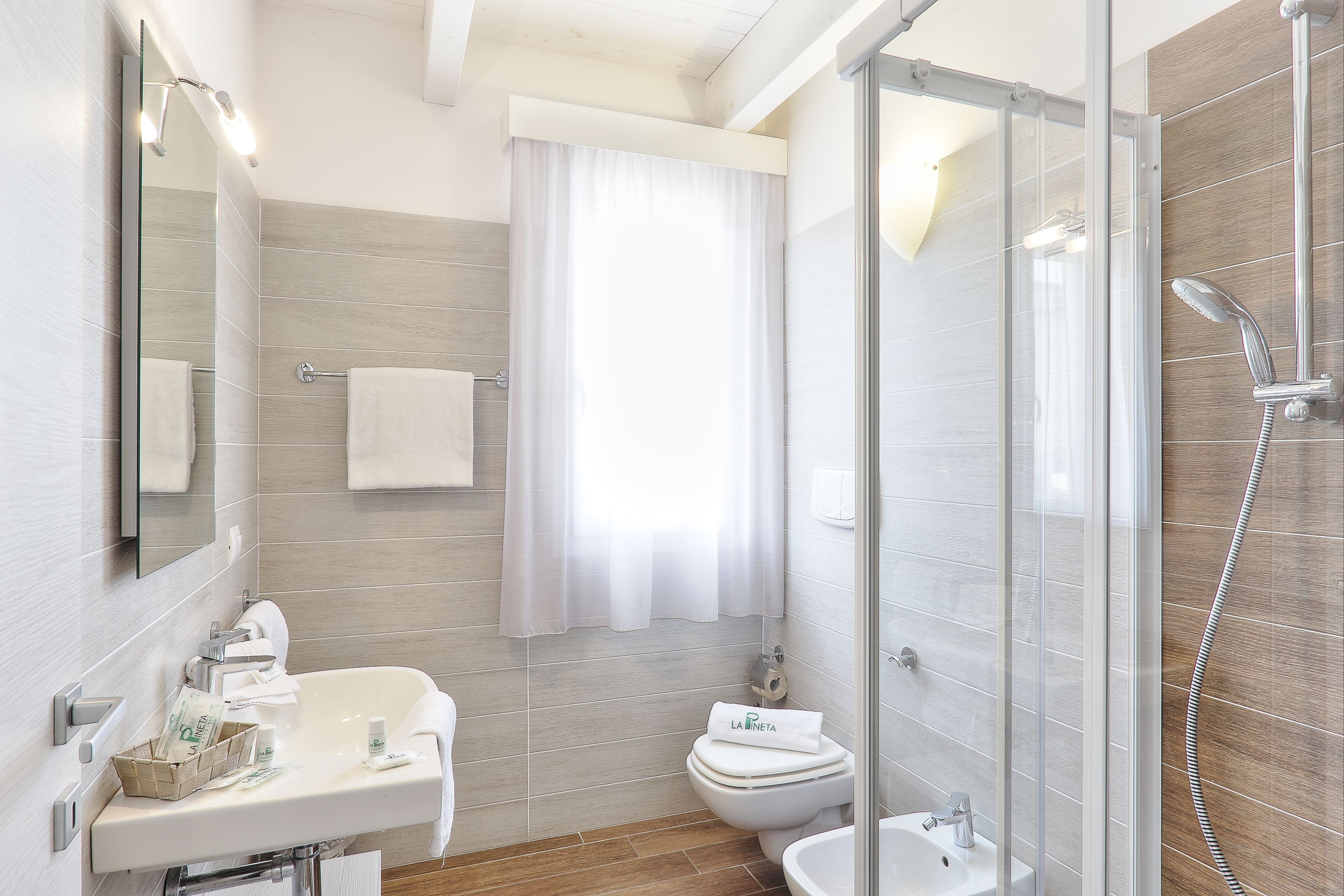 A modern bathroom with a glass-enclosed shower, a sink with toiletries, and a toilet.