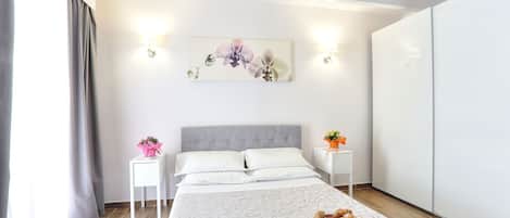 Une chambre d’hôtel moderne équipée d’un lit, de tables de chevet, d’une œuvre d’art accrochée au mur et d’un plateau contenant des articles pour le petit-déjeuner.
