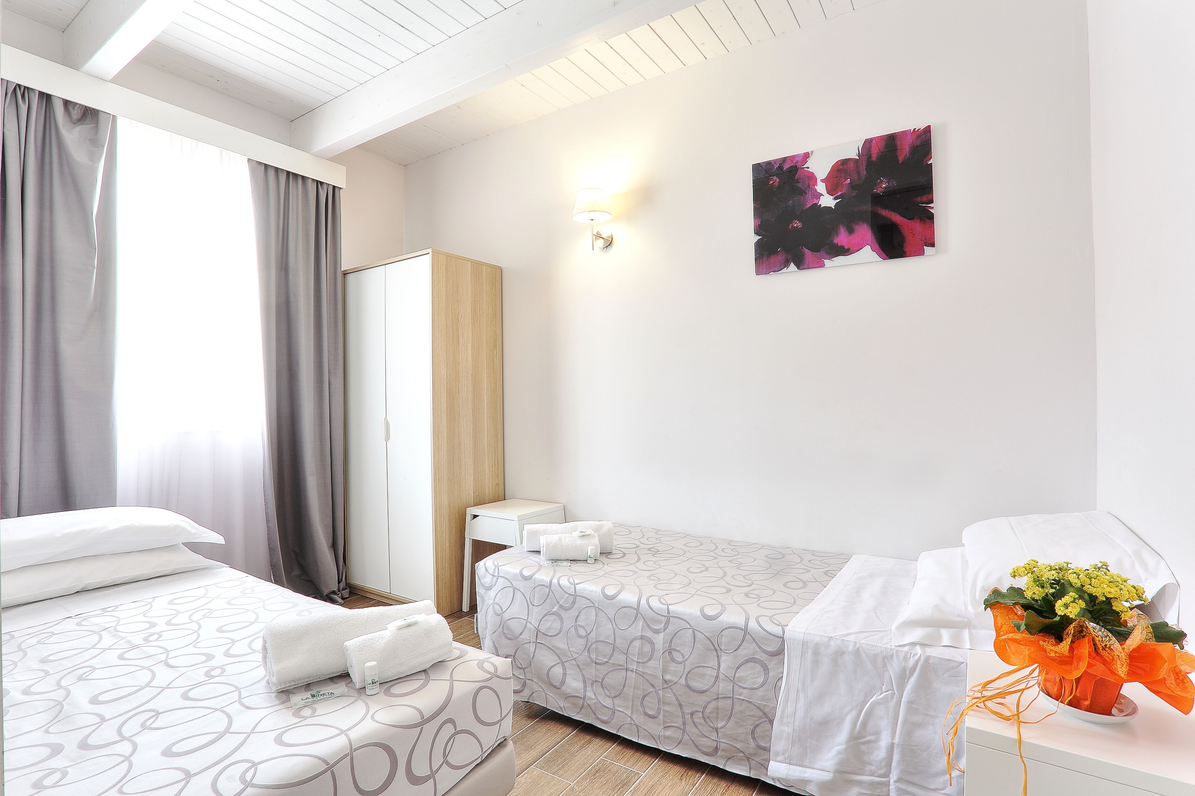 A hotel room with a bed, a bedside table, a wardrobe, and a wall-mounted lamp.
