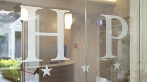 A reception desk with large letters "HP" and stars on a glass window. - Hotel La Pineta (Follonica)