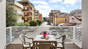 A balcony with a table, chairs, and a view of a street with buildings. - Hotel La Pineta (Follonica)