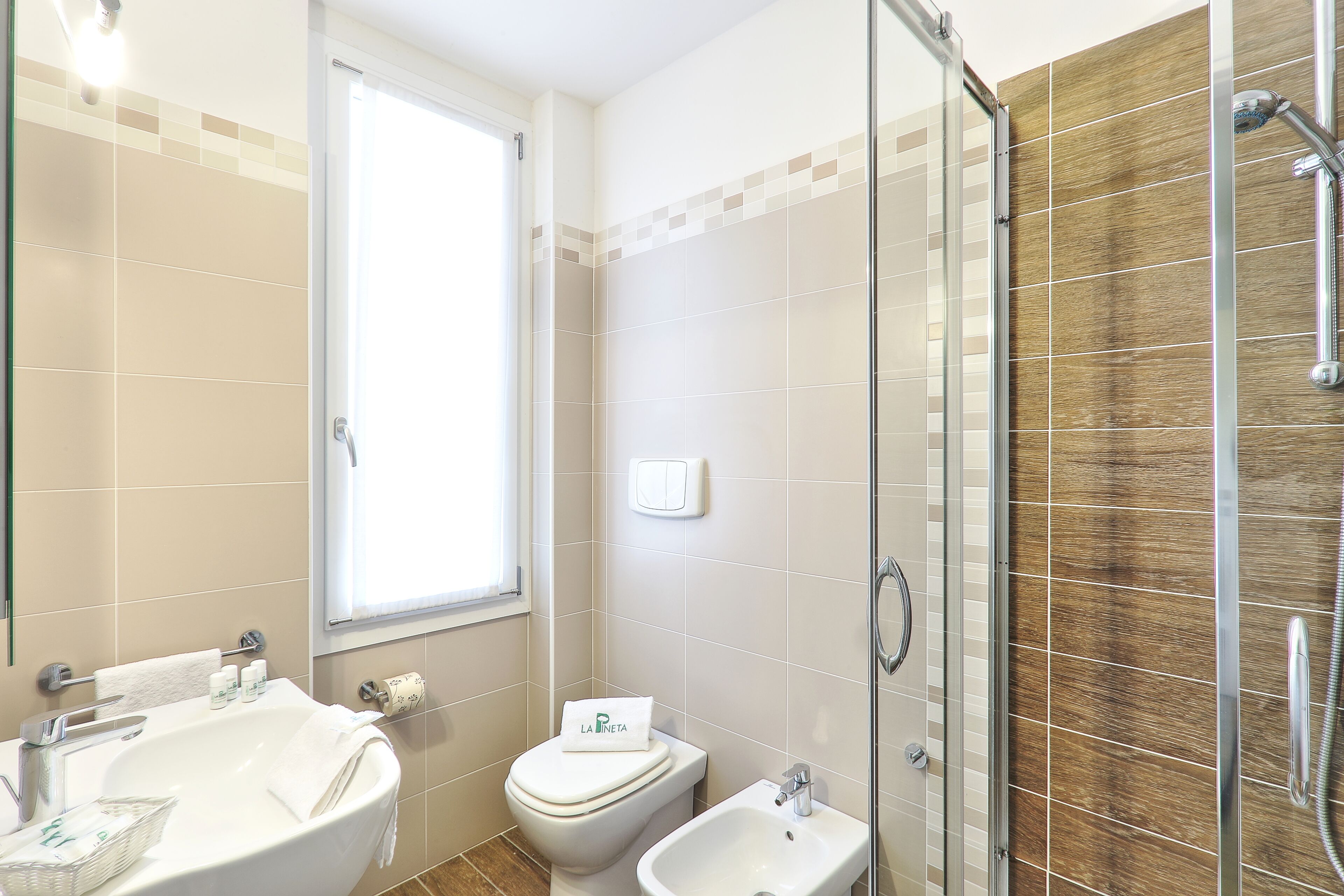 A bathroom with a sink, toilet, bidet, and a glass shower enclosure.