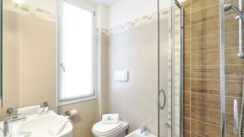 A bathroom with a sink, toilet, bidet, and a glass shower enclosure.