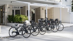 A row of bicycles parked outside a building with a sign that reads "BAR". - Hotel La Pineta (Follonica)