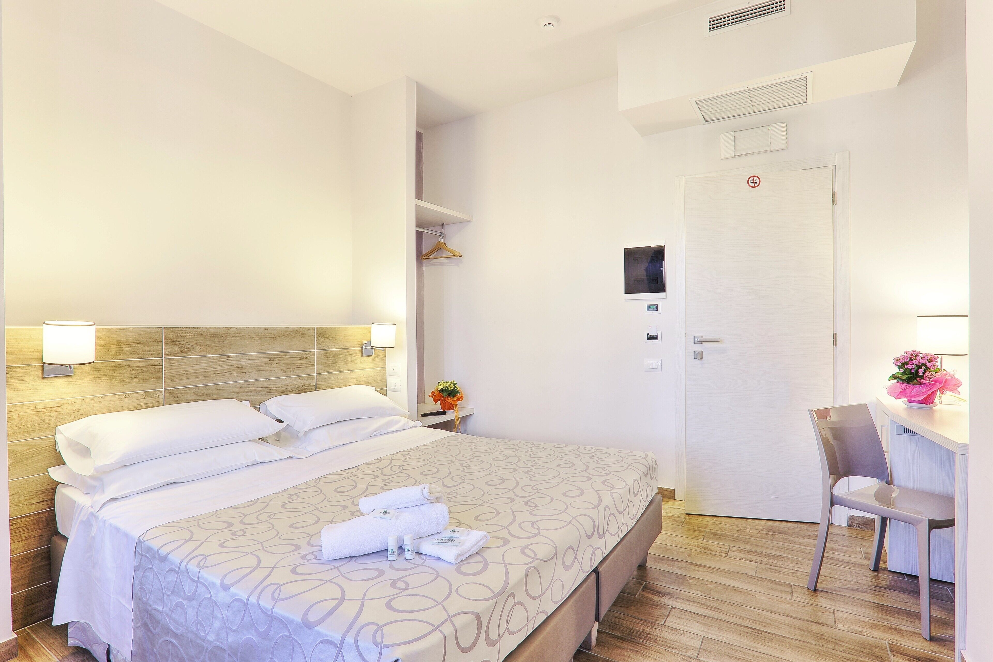 A hotel room with a bed, bedside table, chair, and a door.