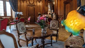 A grand room with ornate wooden paneling, a chandelier, and a round table with chairs. - Domaine du Château de Monrecour – Hôtel et Restaurant (Saint-Vincent-de-Cosse)