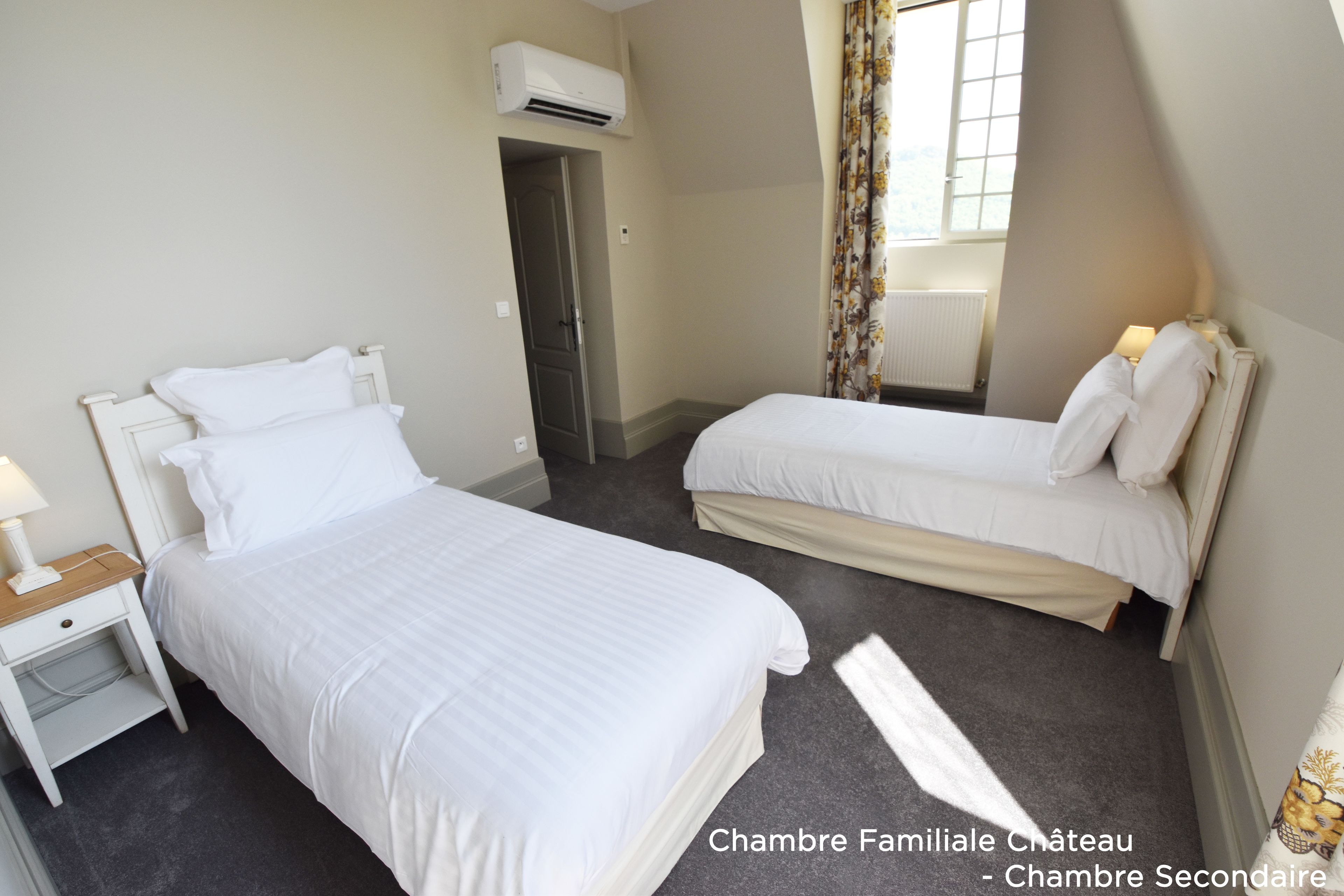 A hotel room with two beds, a nightstand, and an air conditioning unit.
