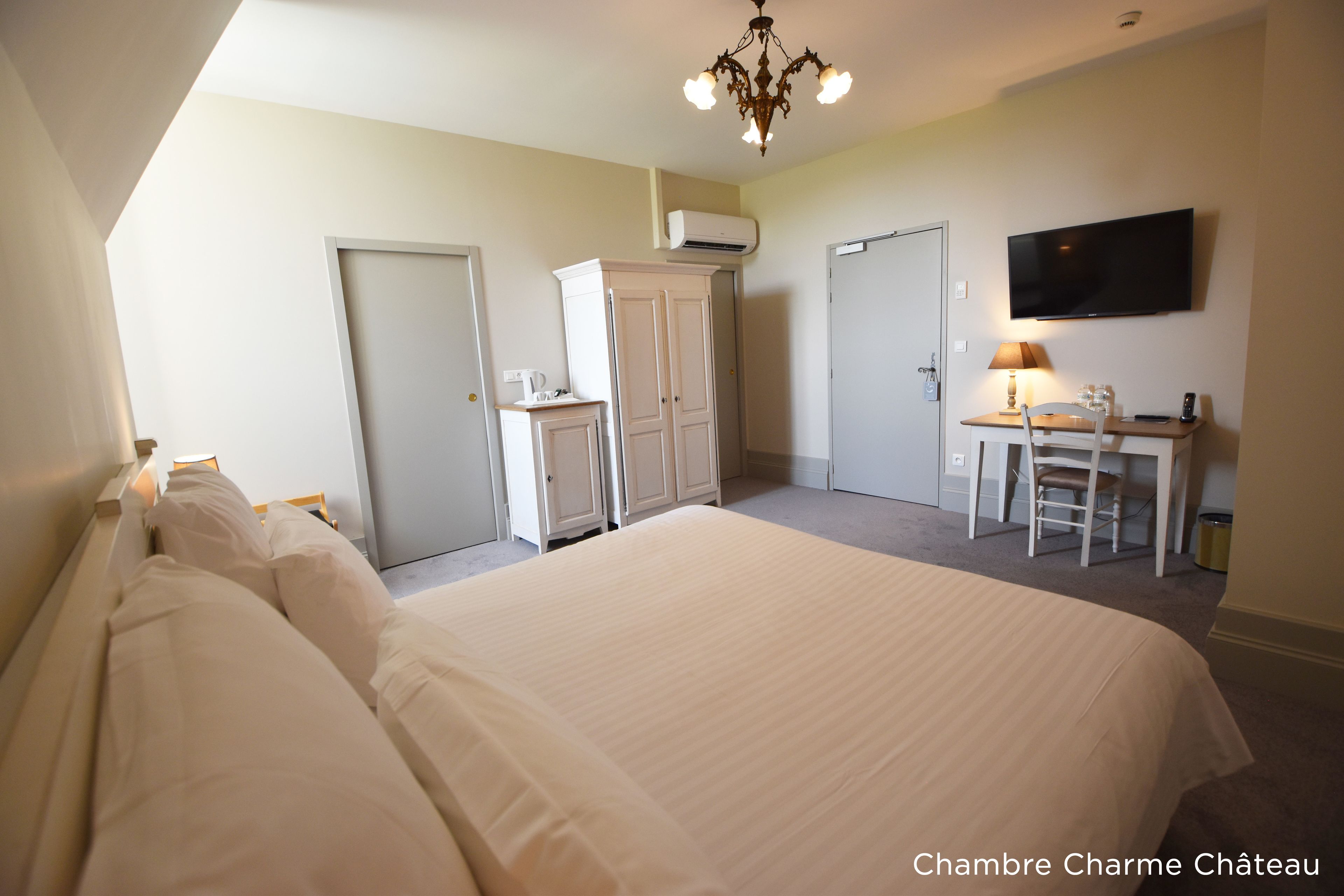 Een slaapkamer met een groot bed, een bureau met stoel, een televisie en een kledingkast.