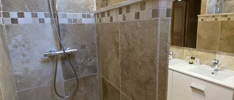 A modern bathroom with a shower, tiled floor, and a vanity with a sink and mirror.