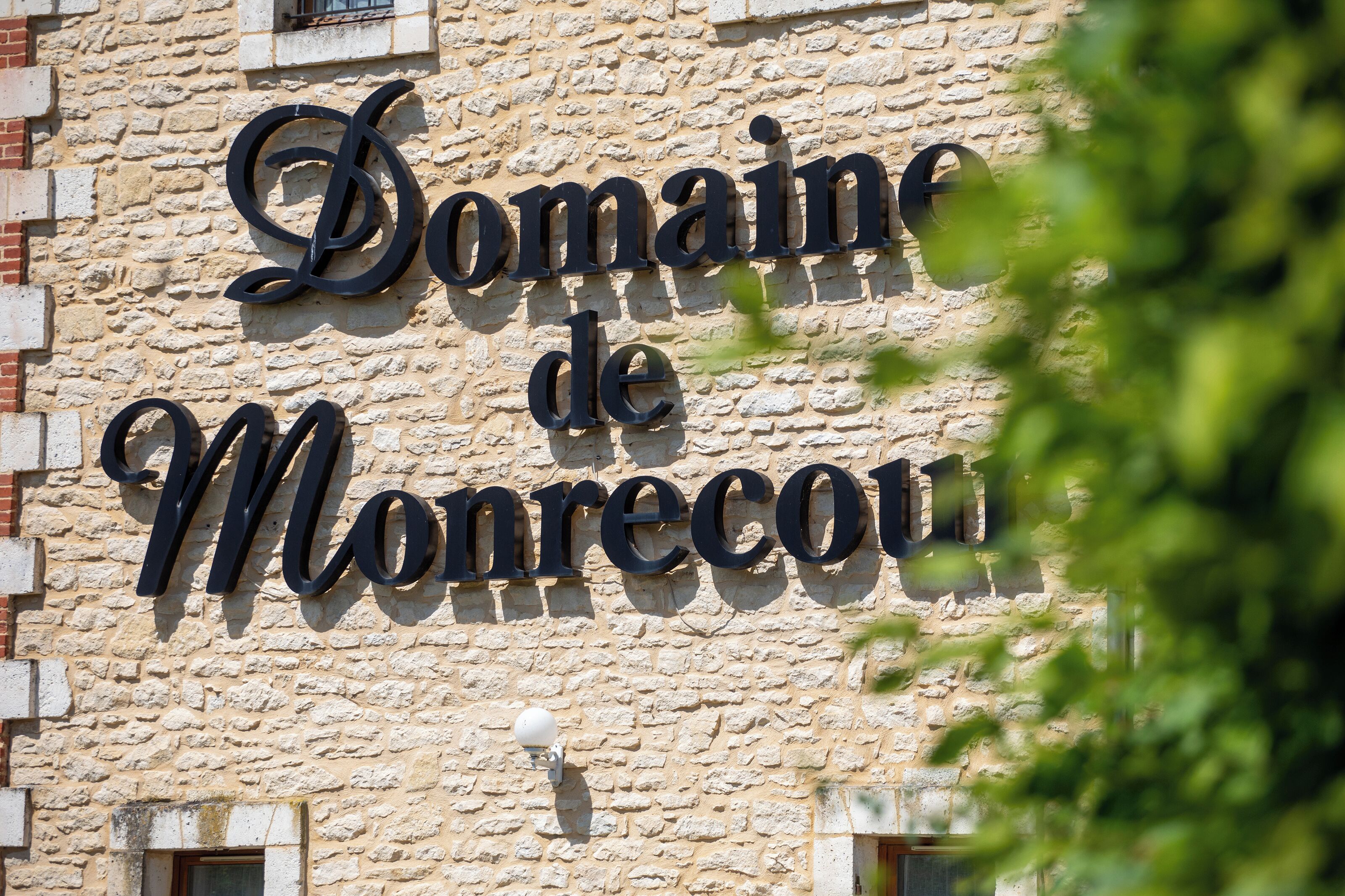 Un bâtiment en pierre sur lequel on peut lire l’inscription « Domaine de Monrecu ».