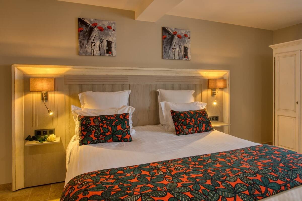 A hotel room with a large bed, two nightstands, a wooden headboard, and two wall-mounted lamps.