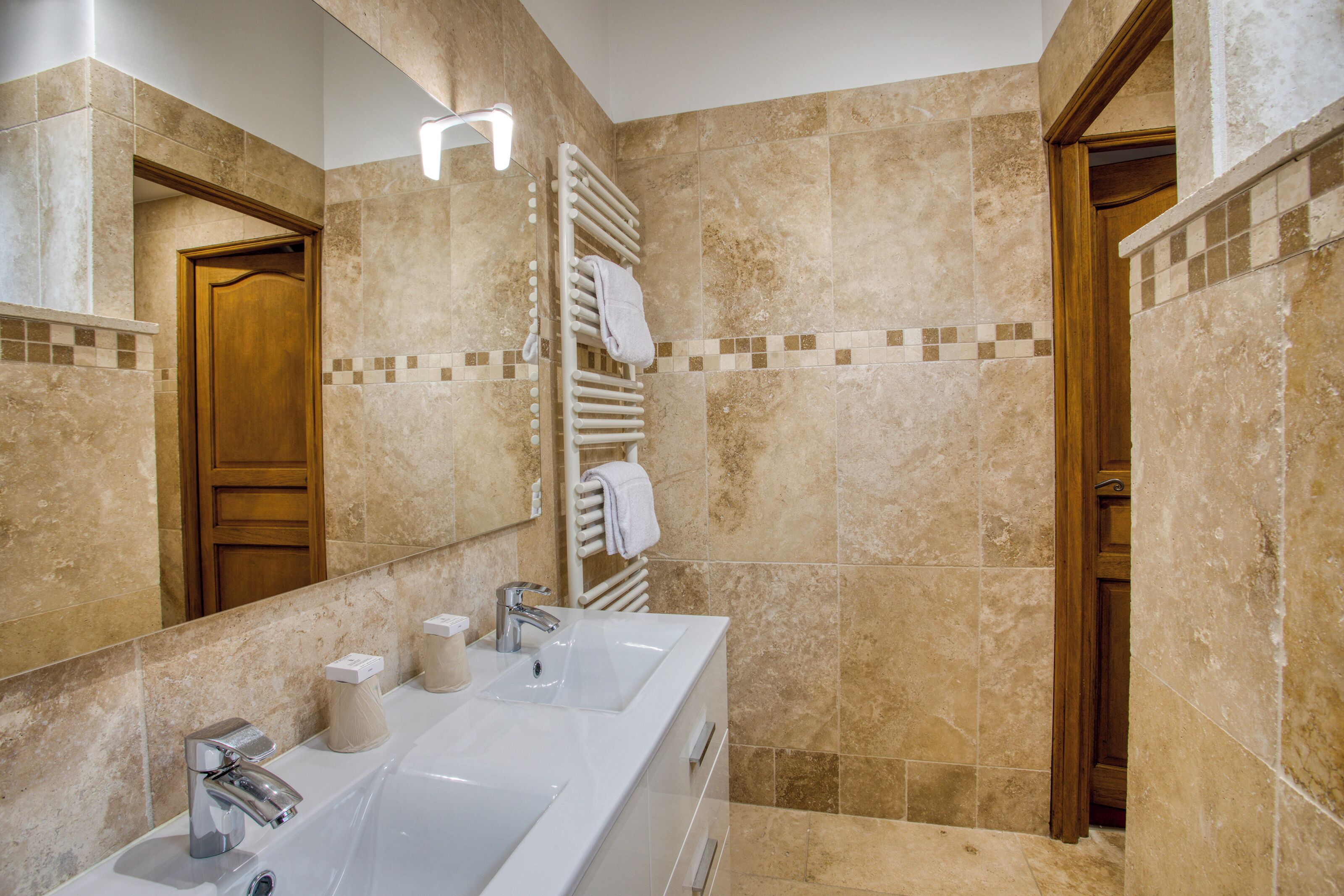 A bathroom with two sinks, a mirror, and a towel rack.