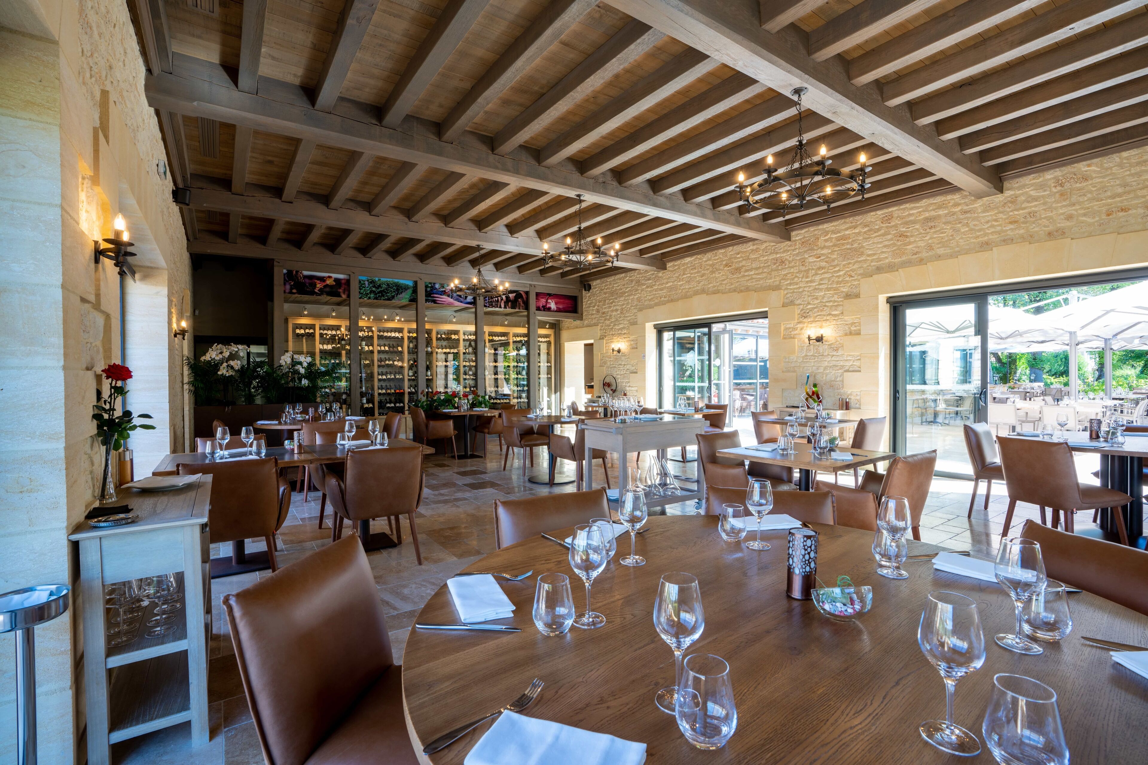 A spacious restaurant with wooden beams, large windows, and a variety of seating arrangements.