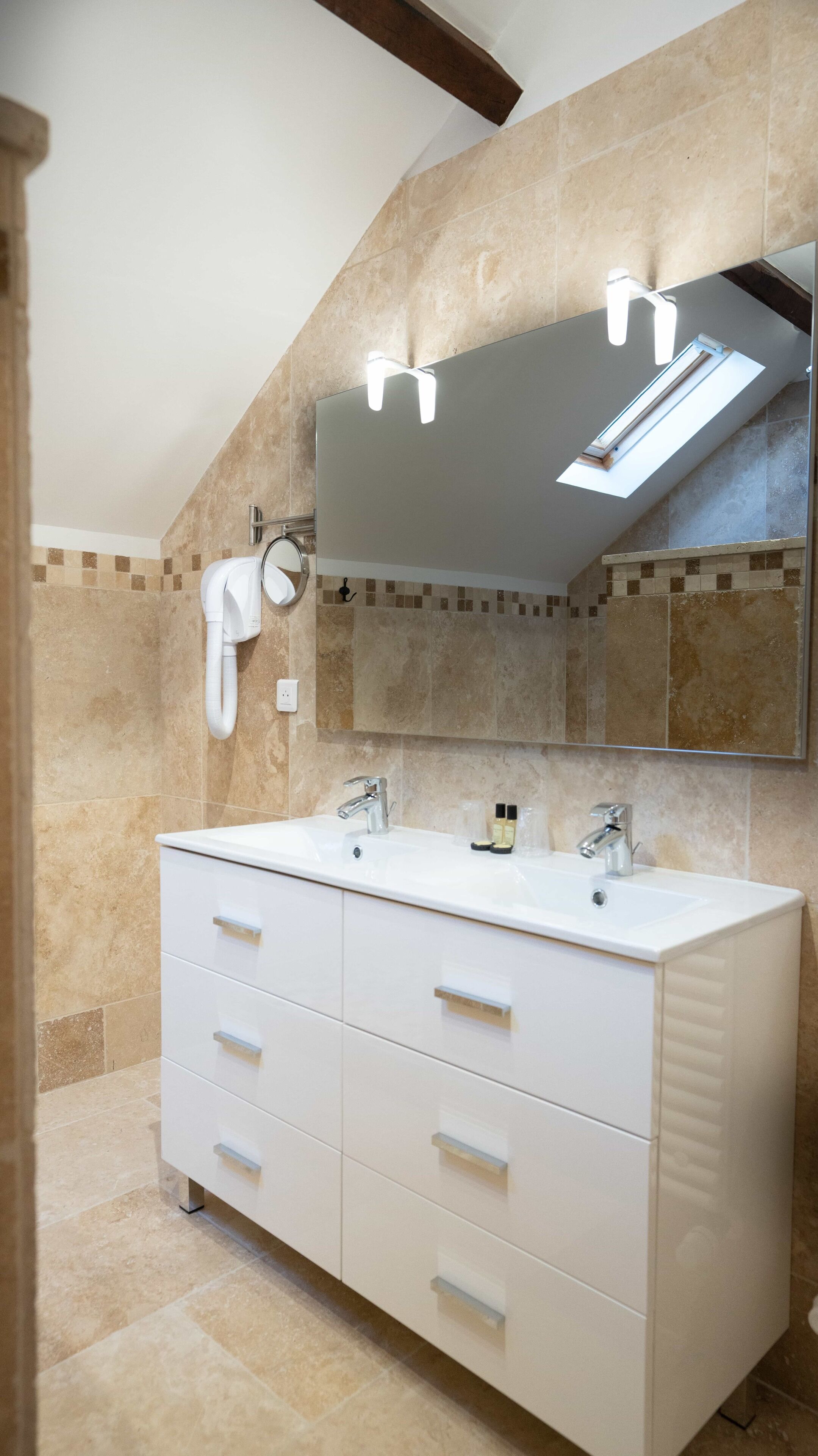 A modern bathroom with a large vanity, a mirror, and a skylight.