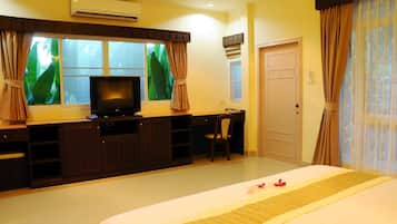A hotel room with a bed, a desk, a television, and a window with curtains.