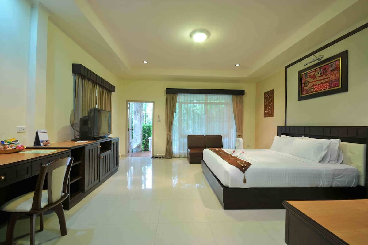 Una habitación de hotel con cama, escritorio, televisión y vistas al exterior.