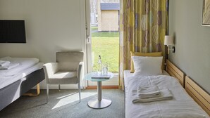 A hotel room with two beds, a chair, a small table with a bottle and glasses, and a view of the outside. - HUSET Middelfart (Middelfart)
