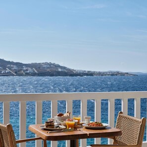 A table with breakfast items and a view of the sea.