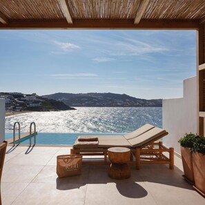 A poolside area with lounge chairs and a view of the sea.