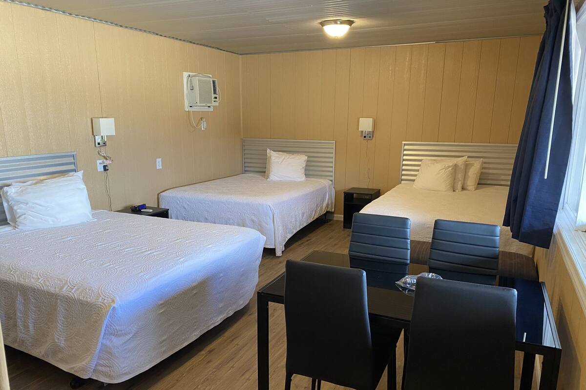 A hotel room with two beds, a desk, and chairs.