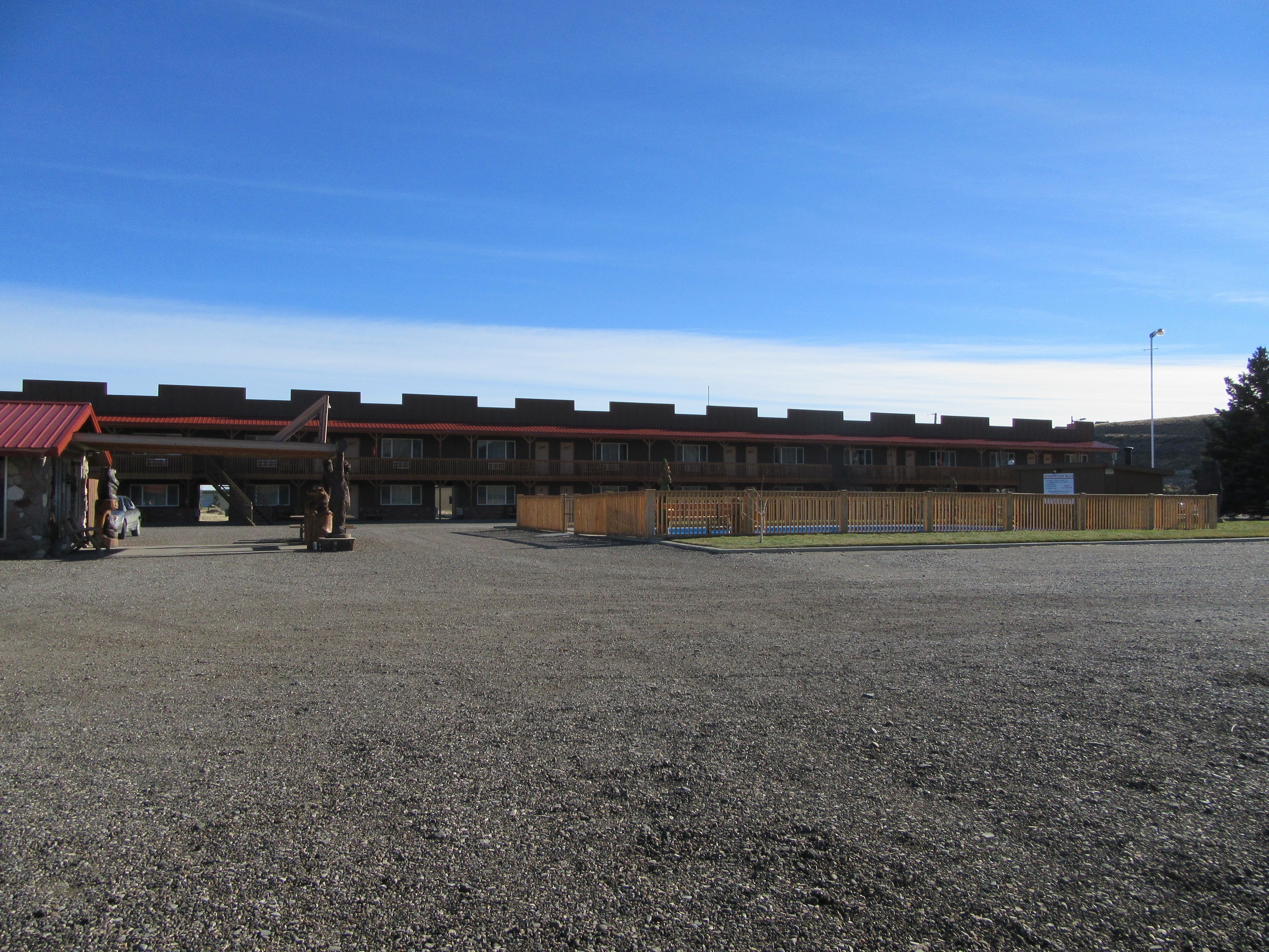 A motel with a red roof and multiple rooms.