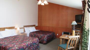 Een hotelkamer met twee bedden, een bureau met stoel, een televisie en een kroonluchter.