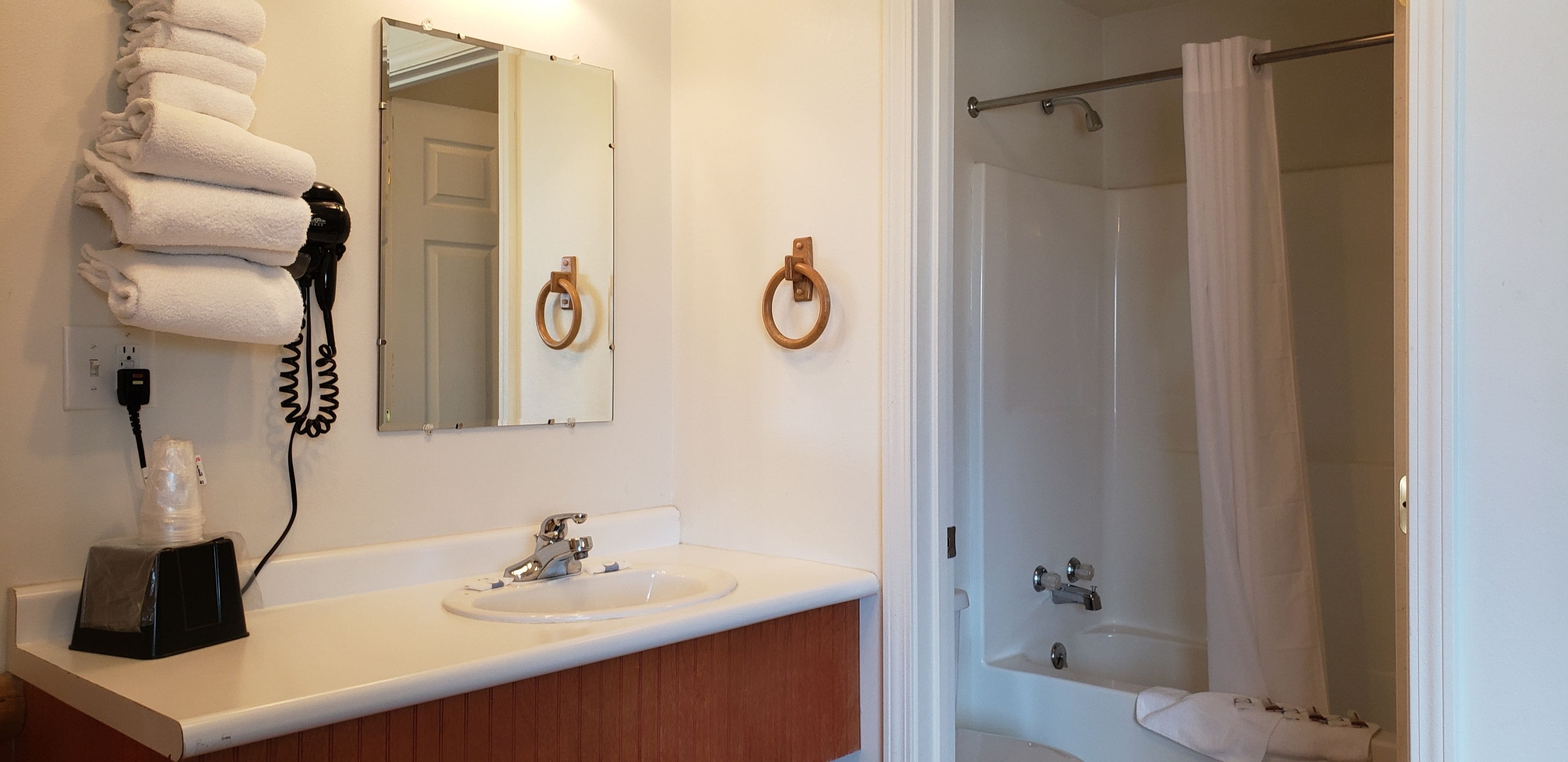 A bathroom with a sink, mirror, towel rack, and shower.