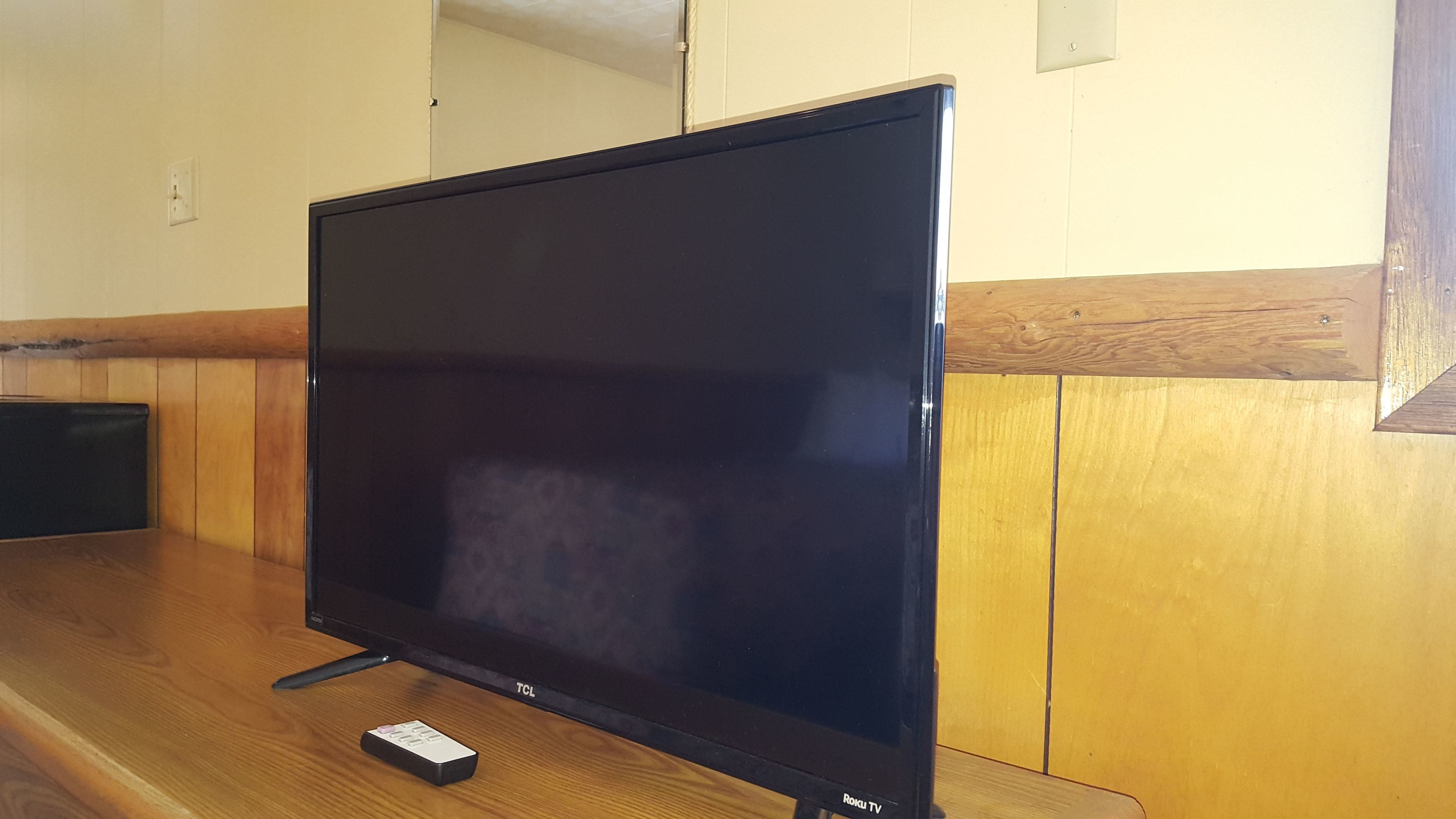 A flat-screen TV on a wooden table in a room with wooden paneling.